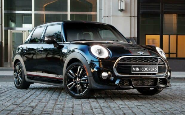 A sleek black Mini Cooper car parked on a stone pavement in front of a modern building, HD Desktop Wallpaper