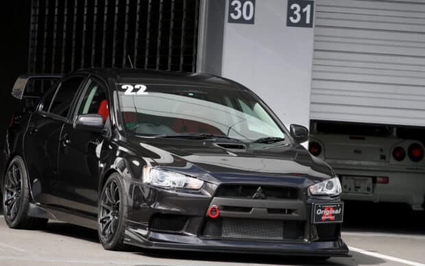 A black Mitsubishi Lancer Evo parked inside a garage with visible racing decals and detailing, HD Desktop Wallpaper