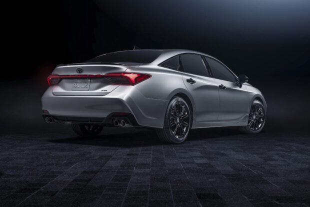 The image shows a sleek silver Toyota Avalon with black wheels on a dark floor, Toyota Avalon Wallpapers, HD Desktop Wallpaper