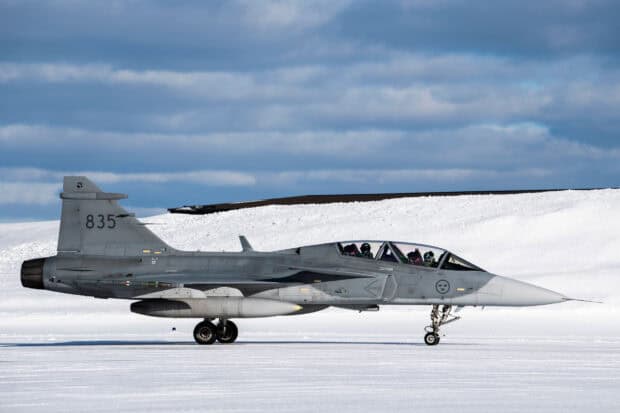 A gray jet fighter is parked on a snowy runway under a cloudy sky, HD Desktop Wallpaper