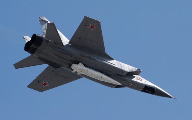 A jet fighter with red star insignias flies high under a clear blue sky, 2K Desktop Wallpaper