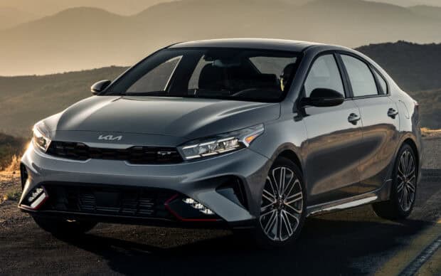 A sleek modern Kia model is parked on a scenic road with mountains in the background, HD Desktop Wallpaper