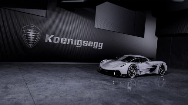 A sleek modern Koenigsegg model is displayed in a dimly lit showroom with its logo on the wall, 2K Desktop Wallpaper