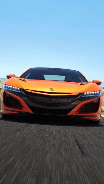 A sleek orange Honda NSX with headlights on is driving on a road under clear sky, HD Mobile Wallpaper