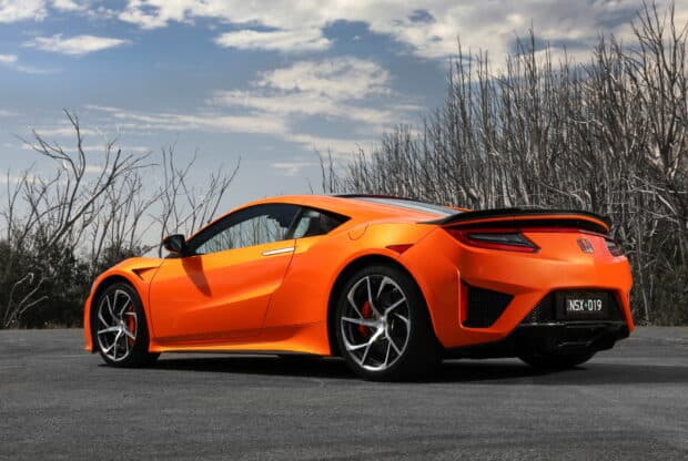 A sleek orange Honda NSX sports car parked near leafless trees under a cloudy sky, HD Desktop Wallpaper