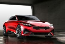 A sleek red Kia car is parked inside a spacious modern garage with concrete walls, 4K Desktop Wallpaper