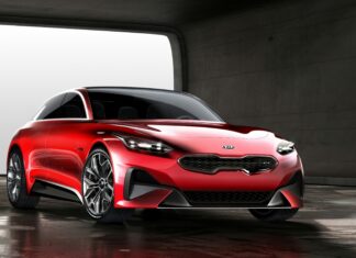 A sleek red Kia car is parked inside a spacious modern garage with concrete walls, 4K Desktop Wallpaper