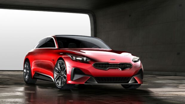 A sleek red Kia car is parked inside a spacious modern garage with concrete walls, 4K Desktop Wallpaper