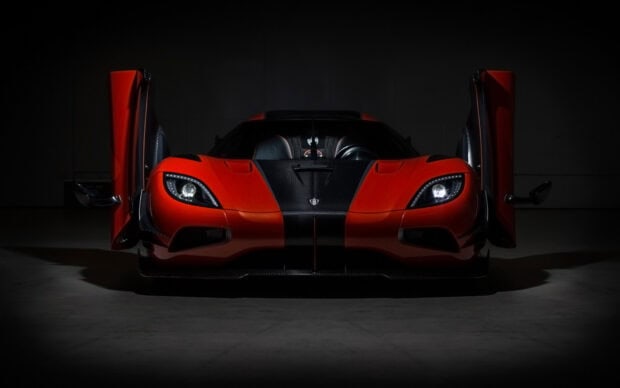 A red Koenigsegg sports car with open butterfly doors is shown in a dark setting highlighting its front design, HD Desktop Wallpaper