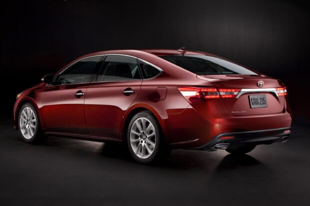 A red Toyota Avalon with bright rear lights is parked in a dark studio setting, 2K Desktop Wallpaper