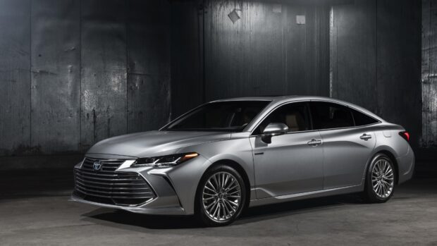 A sleek silver Toyota Avalon is parked in a dark industrial setting showcasing its modern style, 4K Desktop Wallpaper