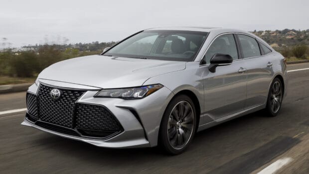 A silver Toyota Avalon is driving on a road with blurred background scenery, HD Desktop Wallpaper