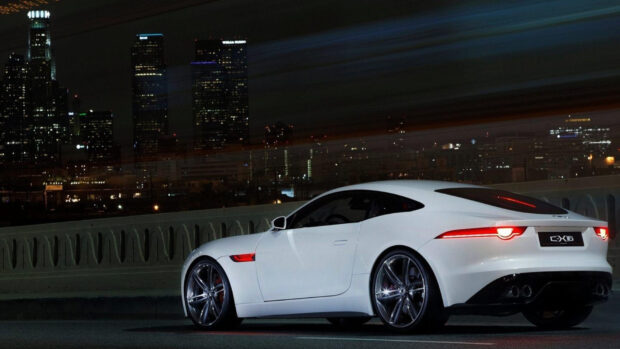 A sleek white Jaguar F Type is parked on a city street with skyscrapers glowing in the background, HD Desktop Wallpaper