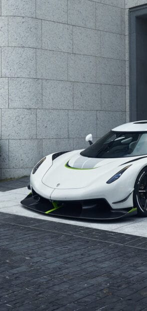 A white Koenigsegg with green accents parked near a stone wall, HD Phone Wallpaper