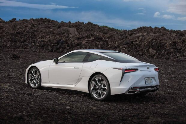 A sleek white Lexus LC is parked on rough black terrain under a cloudy sky, 2K Desktop Wallpaper