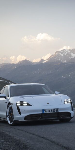 A white Porsche Taycan is parked on a mountain road with scenic peaks in the background, HD Phone Wallpaper