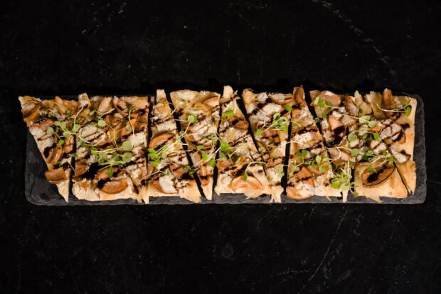 A sliced flatbread dish with mushrooms and fresh greens drizzled with sauce, HD Desktop Wallpaper