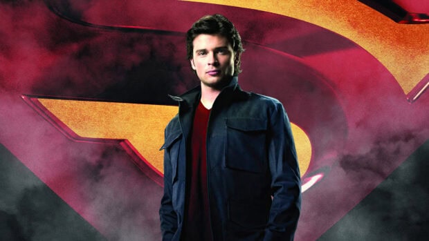 A man stands confidently in front of a red and yellow emblem in Smallville Tv Series wallpapers, 4K Desktop Wallpaper