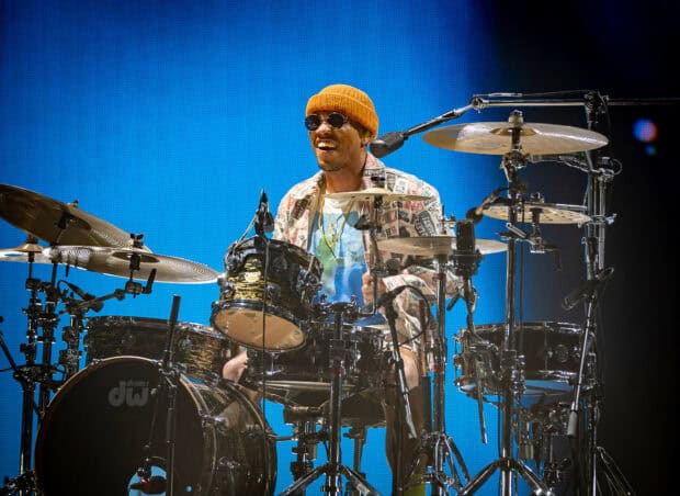 Anderson Paak is performing live while playing drums with a bright blue background, HD Desktop Wallpaper