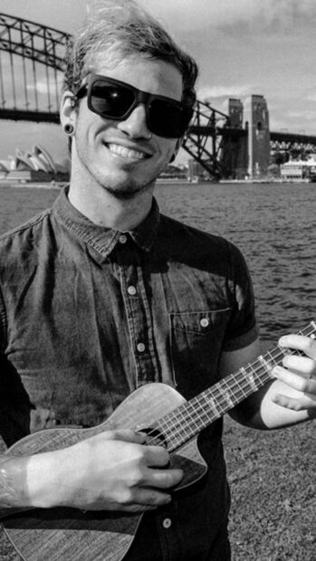 A smiling man wearing sunglasses and playing a ukulele near the Sydney Harbour with Josh Dun Wallpapers, HD Mobile Wallpaper
