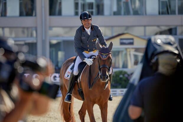 A rider in formal gear smiles while riding a horse in an eventing competition arena, HD Desktop Wallpaper