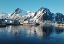 A peaceful village reflects on the water beneath snow capped mountains in the Norwegian fjords, HD Desktop Wallpaper