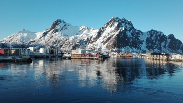 A peaceful village reflects on the water beneath snow capped mountains in the Norwegian fjords, HD Desktop Wallpaper