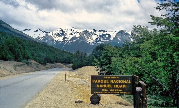 A road leads through Nahuel Huapi with snow capped mountains and green trees, HD Desktop Wallpaper