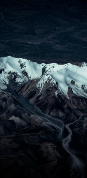 A glacier flows down between snow capped mountains under a dark sky, 2K Phone Wallpaper