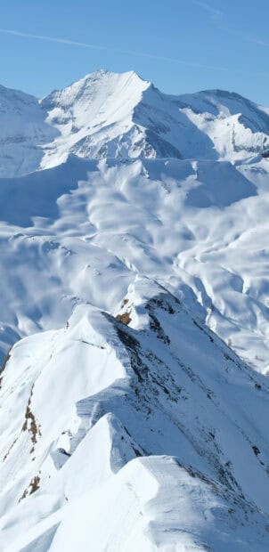 Snow covered mountain peaks rise sharply under a clear blue sky in glacier wallpapers 4K and HD, 2K Mobile Wallpaper