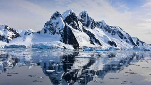 The glacier wallpapers show snowy mountains reflecting on calm icy water under a cloudy sky, 4K Desktop Wallpaper