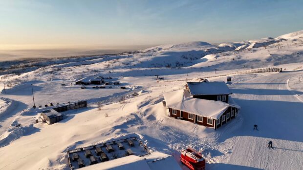 Skiing wallpapers showing skiers on a sunny snow covered slope near cabins, 4K Desktop Wallpaper
