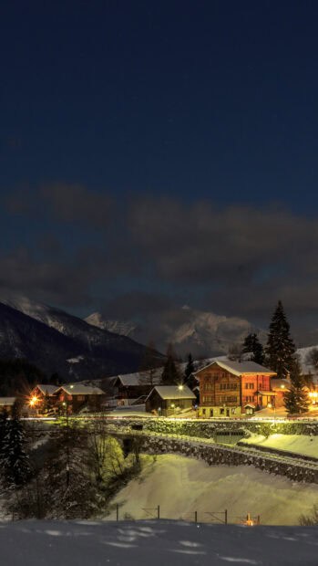 A peaceful village under starry sky covered in snow with wooden houses lit warmly, HD Phone Wallpaper
