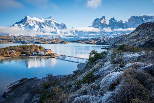 A peaceful lake reflects snowy mountains with vegetation in Torres Del Paine National Park, HD Desktop Wallpaper