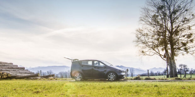 A Sono Motors car is parked on a rural road with mountains and trees in the background, HD Desktop Wallpaper