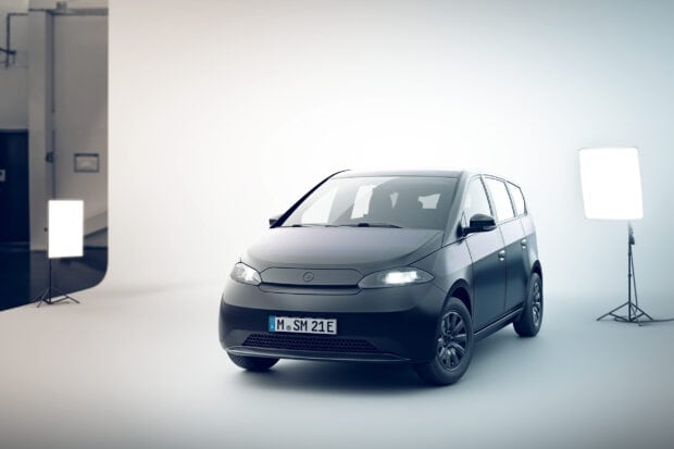 A black Sono Motors electric car is showcased in a studio with bright lighting equipment, 2K Desktop Wallpaper