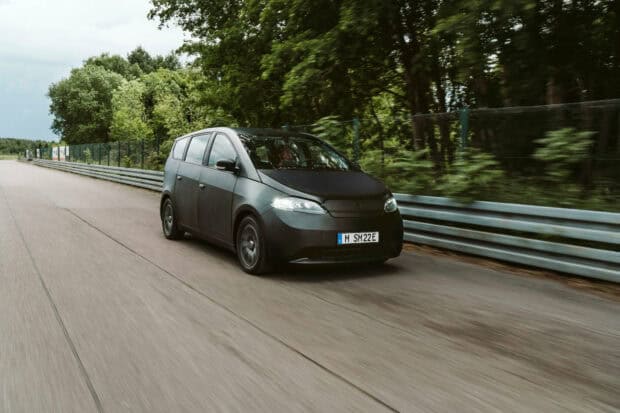 A Sono Motors vehicle is shown driving fast on a highway surrounded by trees, HD Desktop Wallpaper