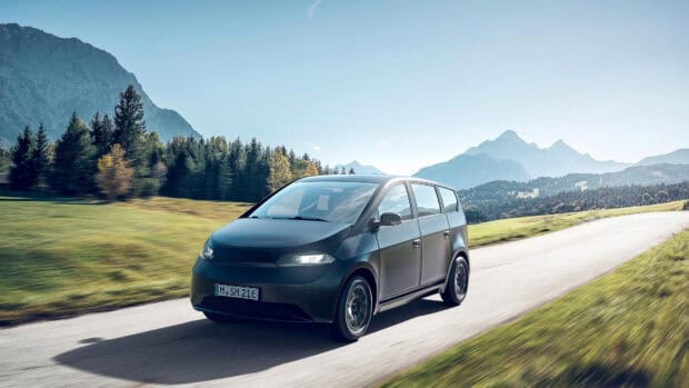A Sono Motors vehicle is driving through a scenic mountain area with clear skies, HD Desktop Wallpaper