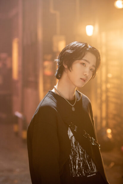 A young man from Soul P1Harmony wearing a black sweater stands in warm ambient light, HD Phone Wallpaper