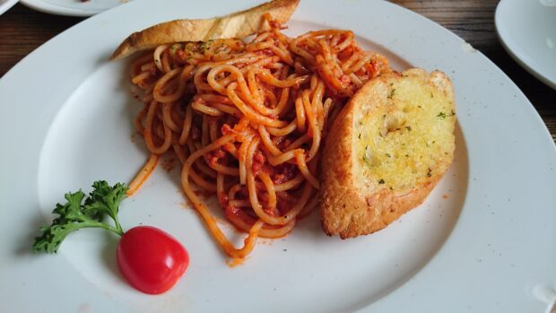 A plate of spaghetti with tomato sauce, garlic bread, and a garnish of parsley and tomato is shown in dish wallpapers, 4K Desktop Wallpaper