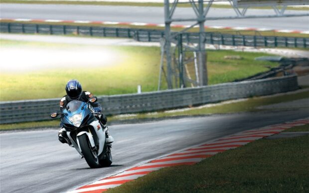 A motorcyclist is riding fast on a race track during a sunny day, HD Desktop Wallpaper