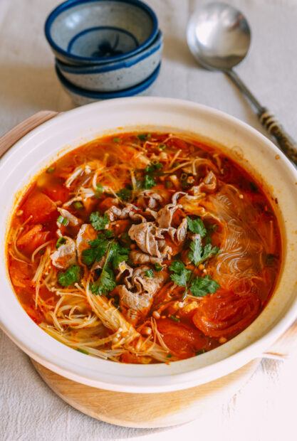 A bowl of spicy soup with enoki mushrooms and herbs on a table, HD Mobile Wallpaper
