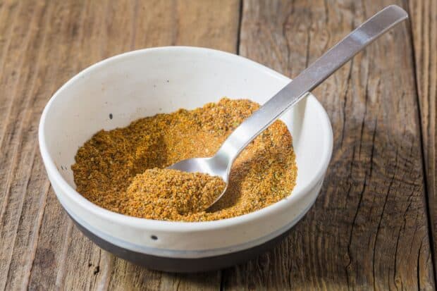 A close up of seasoning mix in a white bowl with a spoon inside on a wooden table, HD Desktop Wallpaper