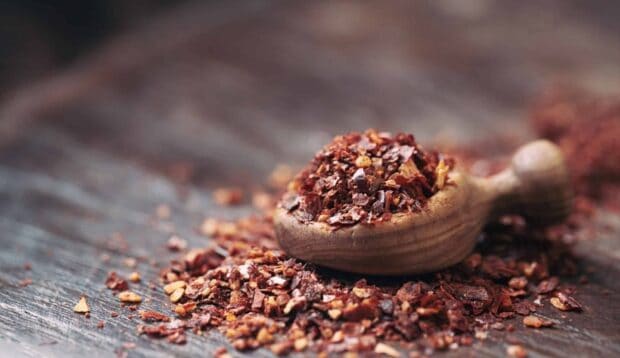 A wooden scoop filled with a spicy seasoning mix rests on a rustic wooden surface, HD Desktop Wallpaper
