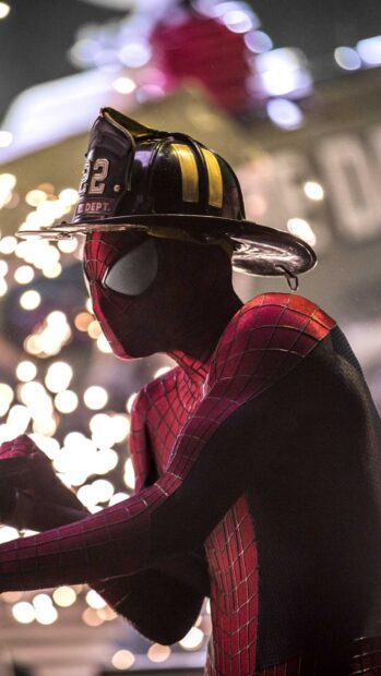 Spider Man Andrew Garfield wears a firefighter helmet with bright lights in the background, HD Mobile Wallpaper