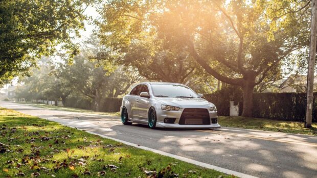 A silver Lancer Evo is parked on a quiet tree lined street bathed in warm sunlight, HD Desktop Wallpaper