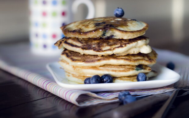 A stack of blueberry pancakes topped with syrup and fresh blueberries on a white plate, HD Desktop Wallpaper