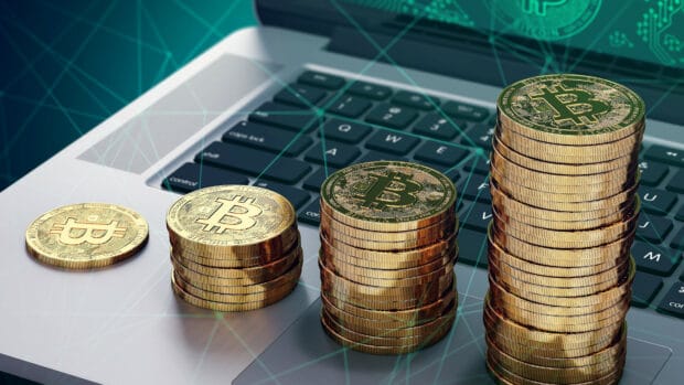 Golden bitcoins in stacks on a laptop keyboard symbolizing digital currency growth, 4K Desktop Wallpaper