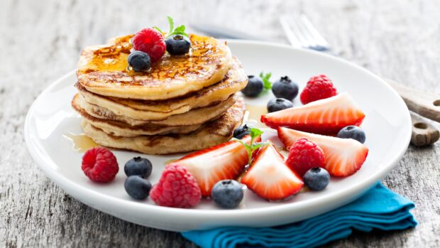 A stack of pancakes topped with fresh berries and syrup on a white plate, 4K Desktop Wallpaper
