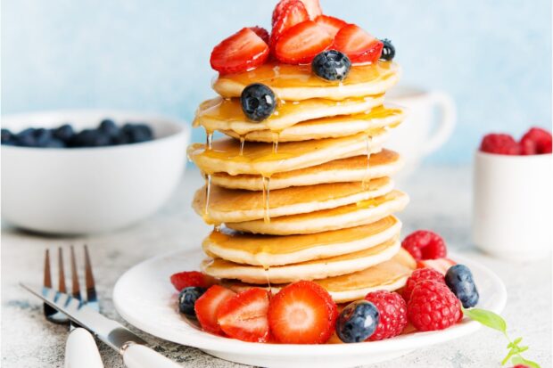 A stack of pancakes topped with strawberries blueberries and syrup on a white plate, 2K Desktop Wallpaper